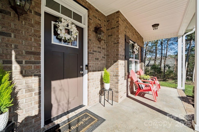 view of exterior entry with covered porch and brick siding