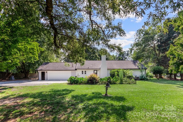 single story home featuring a garage, driveway, a chimney, and a front lawn