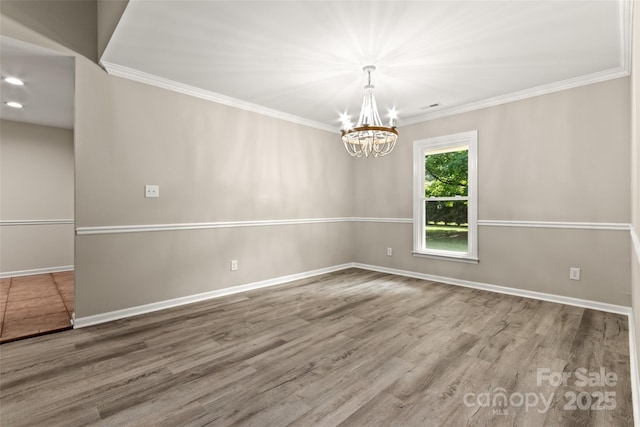 empty room featuring baseboards, visible vents, ornamental molding, and wood finished floors