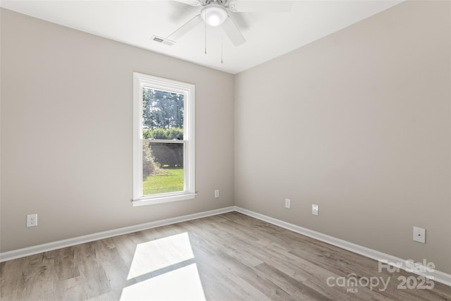 spare room featuring a ceiling fan, baseboards, visible vents, and light wood finished floors