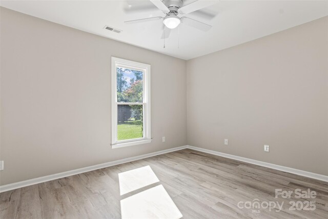 spare room featuring baseboards, a ceiling fan, visible vents, and light wood-style floors