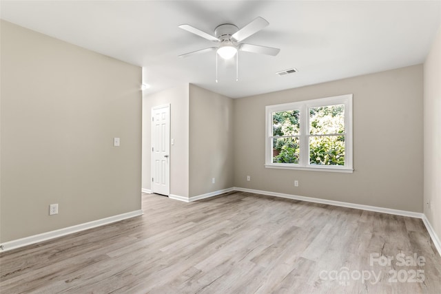 spare room featuring light wood-style floors, visible vents, and baseboards