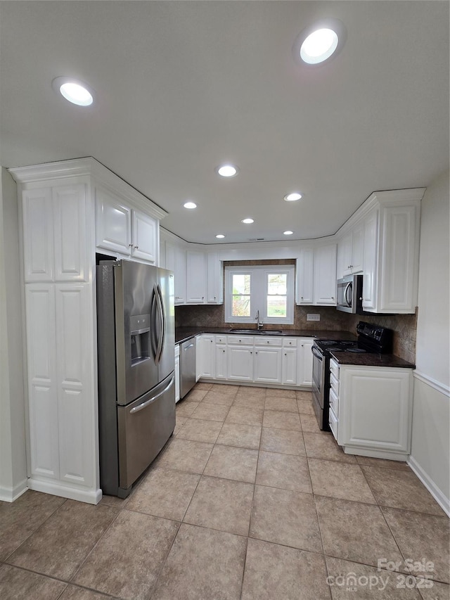 kitchen with dark countertops, appliances with stainless steel finishes, backsplash, and a sink