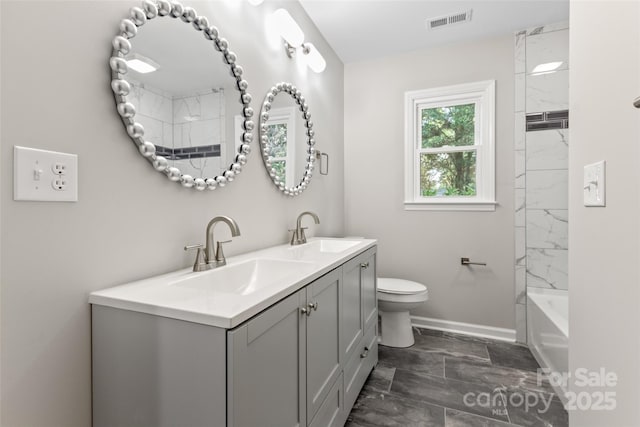 bathroom with visible vents, a sink, toilet, and double vanity