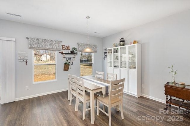 dining area with dark wood finished floors, visible vents, and baseboards