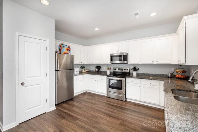 kitchen featuring stainless steel appliances, dark wood-style flooring, white cabinetry, and a sink