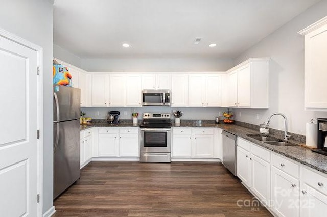 kitchen featuring stainless steel appliances, dark wood-style flooring, a sink, and white cabinets