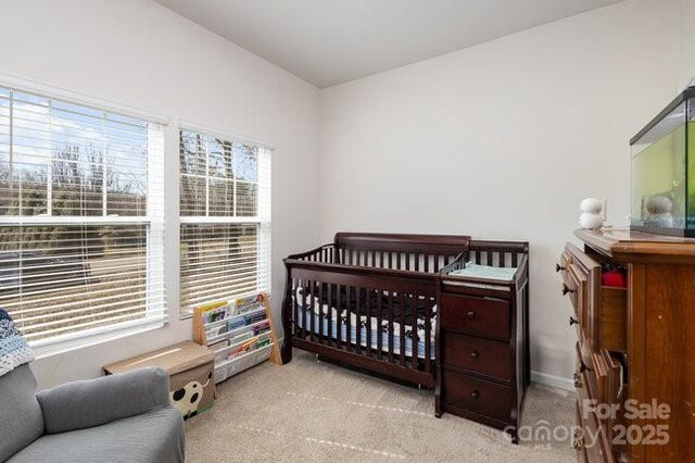 bedroom featuring a crib, carpet, and baseboards