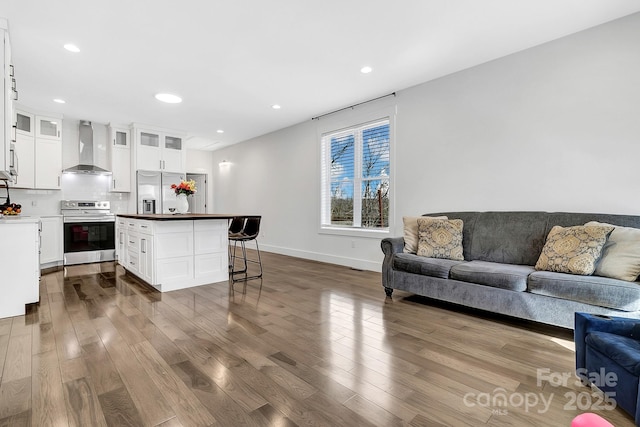 kitchen featuring white cabinets, a center island, appliances with stainless steel finishes, and wall chimney exhaust hood