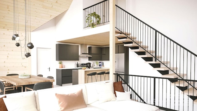 interior space featuring wall chimney range hood, range, a high ceiling, and fridge