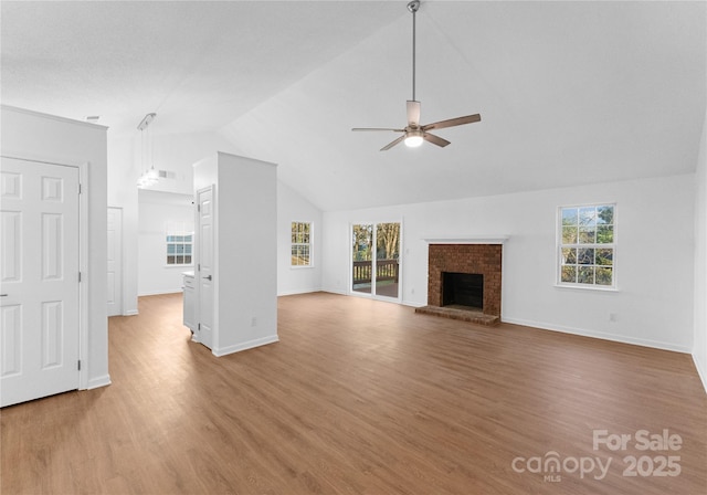 unfurnished living room featuring a fireplace, wood finished floors, a wealth of natural light, and a ceiling fan