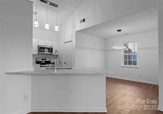 kitchen featuring visible vents, wood finished floors, stainless steel appliances, white cabinetry, and a sink