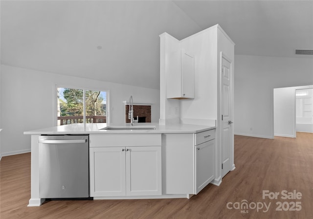 kitchen featuring a sink, white cabinets, light countertops, stainless steel dishwasher, and light wood-type flooring