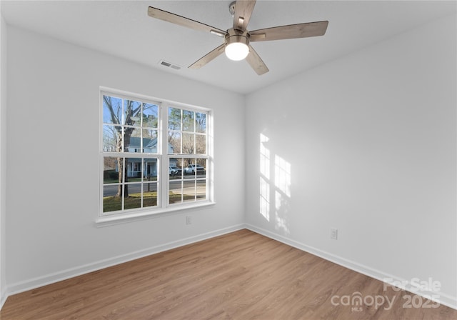 empty room featuring baseboards, visible vents, ceiling fan, and wood finished floors