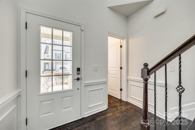 entryway featuring stairway, a decorative wall, dark wood-style flooring, and wainscoting