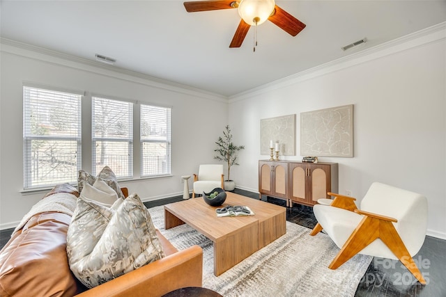 living area with baseboards, visible vents, ceiling fan, and crown molding