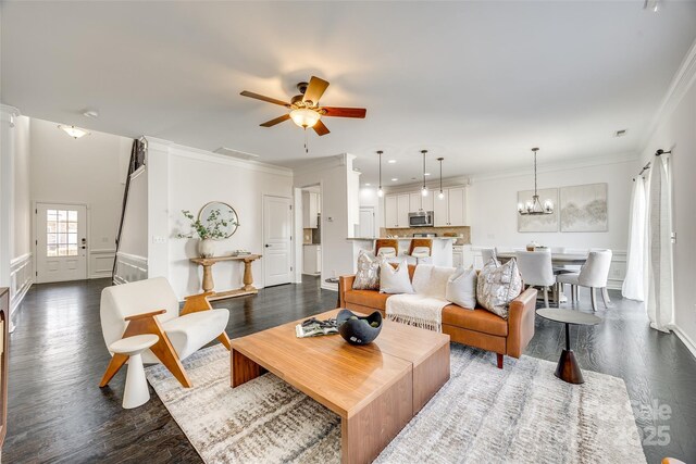 living area with ornamental molding, dark wood-style flooring, and ceiling fan with notable chandelier