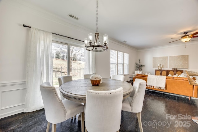 dining area with dark wood-style floors, visible vents, ornamental molding, and ceiling fan with notable chandelier