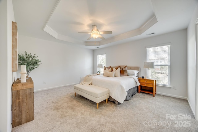 bedroom with light colored carpet, a ceiling fan, baseboards, visible vents, and a tray ceiling