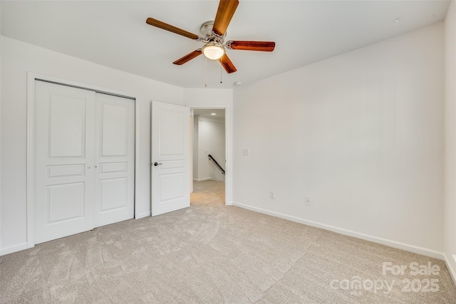 unfurnished bedroom with ceiling fan, baseboards, a closet, and light colored carpet