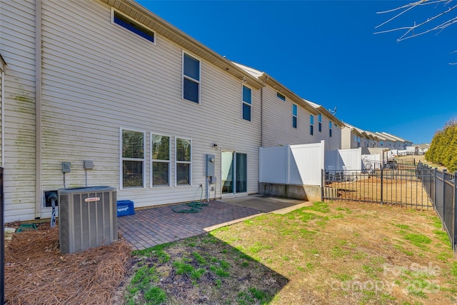 rear view of property with a fenced backyard, central AC, and a patio