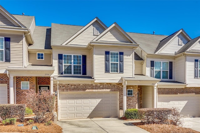 townhome / multi-family property featuring a garage, concrete driveway, and brick siding