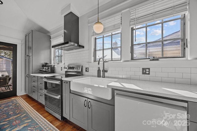 kitchen with stainless steel appliances, a sink, gray cabinets, dark wood-style floors, and island exhaust hood