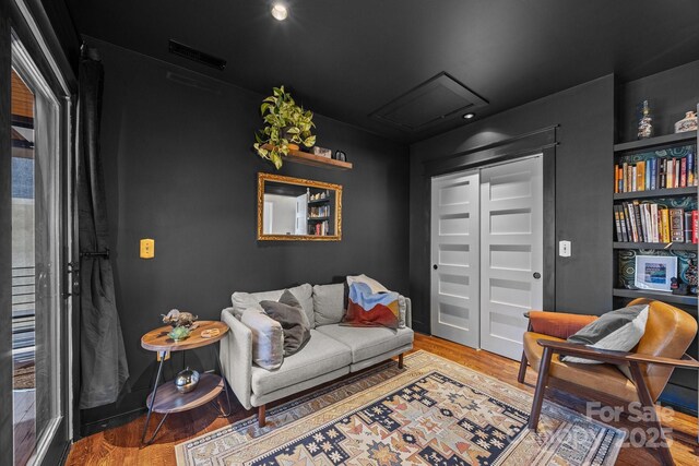 living area with attic access, visible vents, and wood finished floors