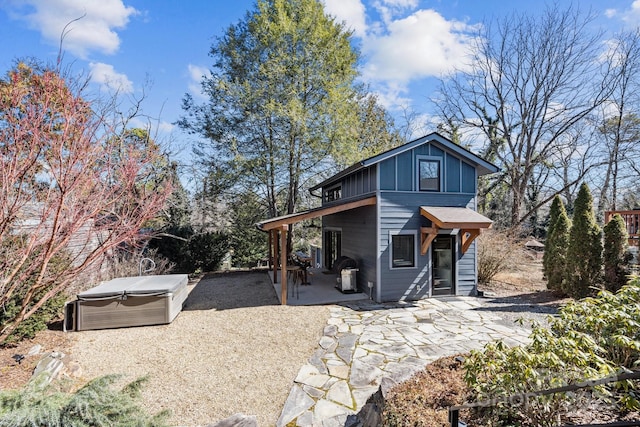 view of front of home with a patio, board and batten siding, and a hot tub