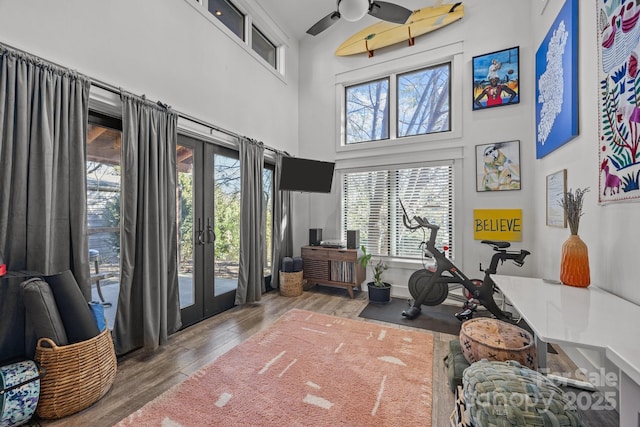 workout room featuring french doors, a towering ceiling, and wood finished floors