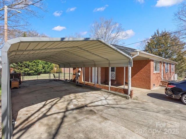 view of vehicle parking with a carport, driveway, and fence