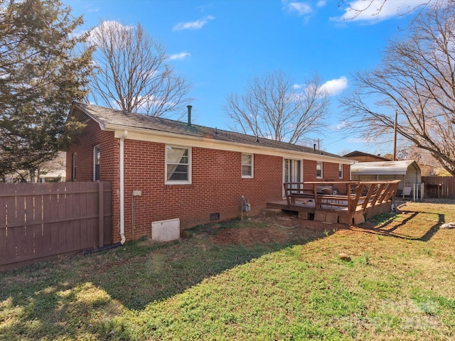 back of property featuring brick siding, crawl space, fence, and a lawn