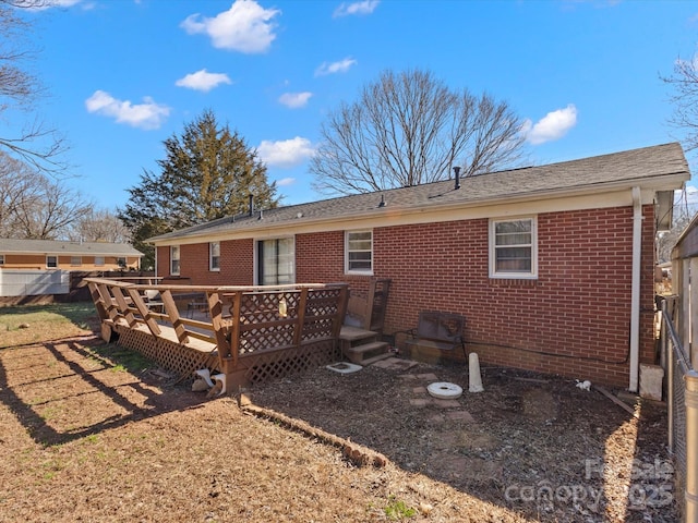 rear view of property featuring a deck and brick siding