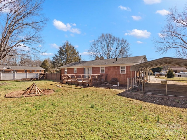 back of house featuring a lawn, a detached carport, fence, a wooden deck, and brick siding