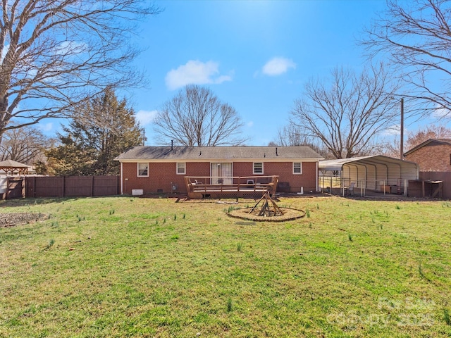 rear view of house with a deck, fence, a yard, crawl space, and a detached carport