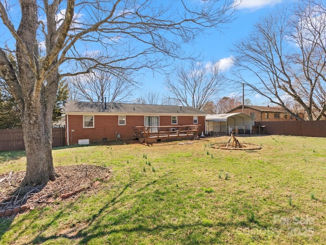 rear view of house with a wooden deck, fence, a lawn, and brick siding