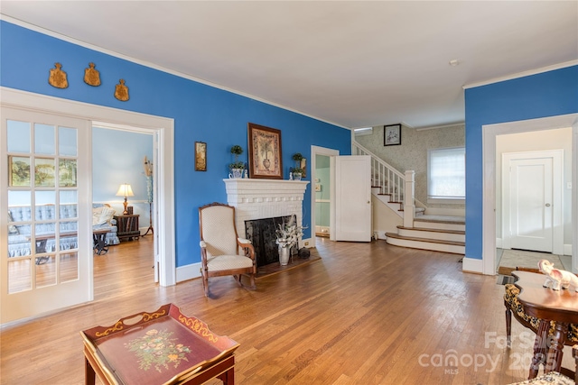 living room featuring stairway, a fireplace, wood finished floors, and baseboards