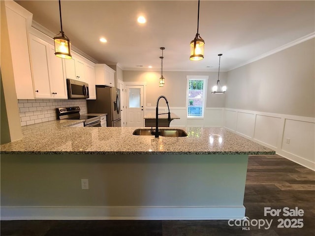 kitchen with kitchen peninsula, hanging light fixtures, sink, appliances with stainless steel finishes, and white cabinets