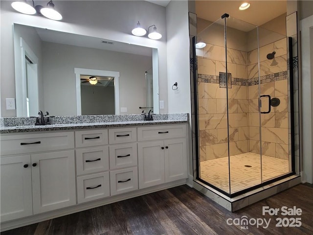 bathroom with ceiling fan, vanity, an enclosed shower, and wood-type flooring