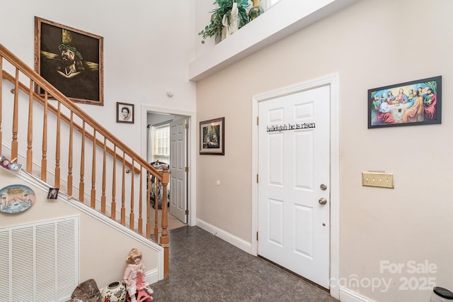 entrance foyer featuring a high ceiling, stairway, and baseboards