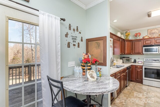 kitchen with ornamental molding, a kitchen breakfast bar, stainless steel appliances, light countertops, and a sink