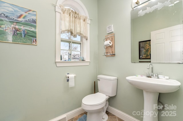 half bathroom featuring toilet and baseboards