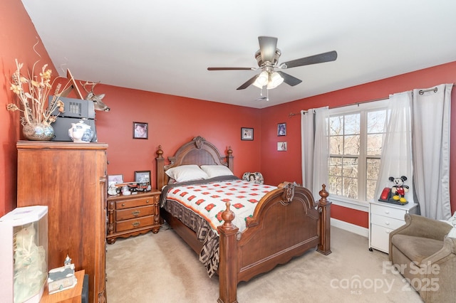 bedroom with a ceiling fan, light carpet, and baseboards