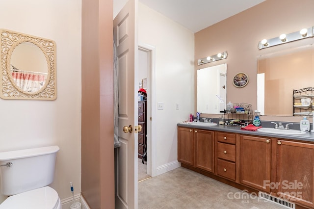 bathroom featuring toilet, double vanity, visible vents, and a sink