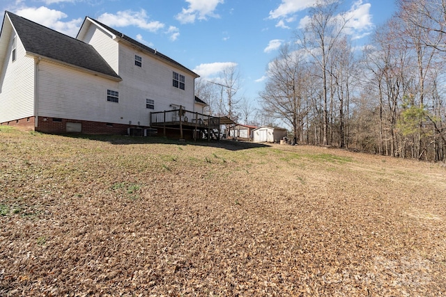 view of yard featuring central air condition unit, a storage shed, an outbuilding, and a wooden deck