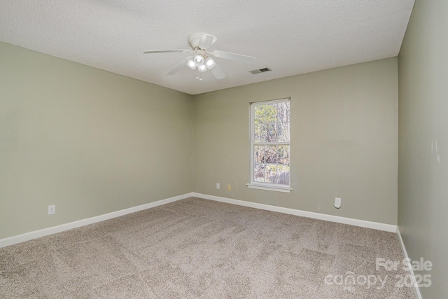 empty room with a textured ceiling, carpet, a ceiling fan, and baseboards