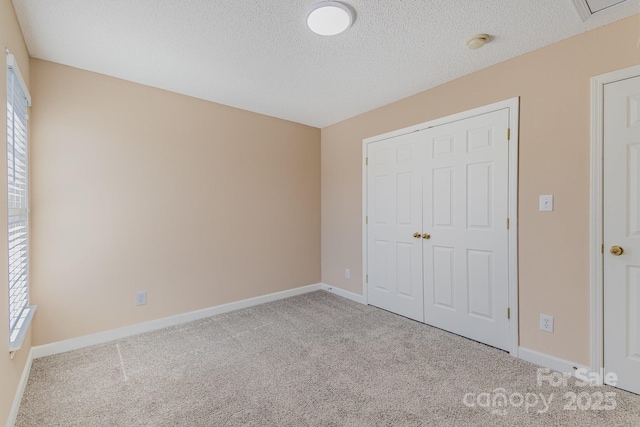 unfurnished bedroom with a closet, carpet flooring, a textured ceiling, and baseboards