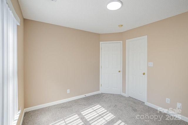 unfurnished bedroom featuring carpet floors and baseboards