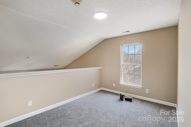 additional living space featuring carpet, vaulted ceiling, a textured ceiling, and baseboards