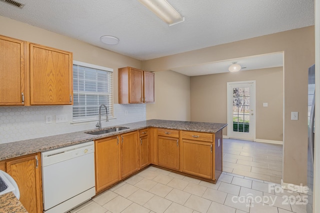 kitchen with tasteful backsplash, visible vents, a sink, dishwasher, and a peninsula